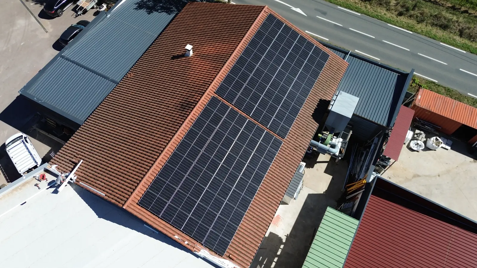 Panneaux photovoltaïques Trina Solar sur la toiture d'une menuiserie à Saint-Étienne-des-Oullières (69), vue de drone